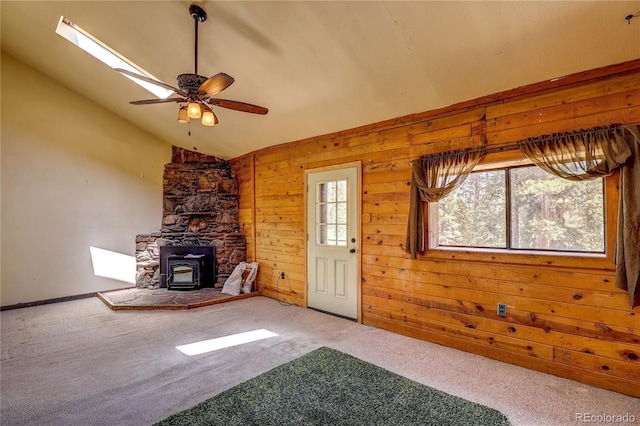 10893 Milliken Ave, Conifer, CO 80433 - unfurnished living room with a wood stove, vaulted ceiling, carpet, ceiling fan, and wooden walls