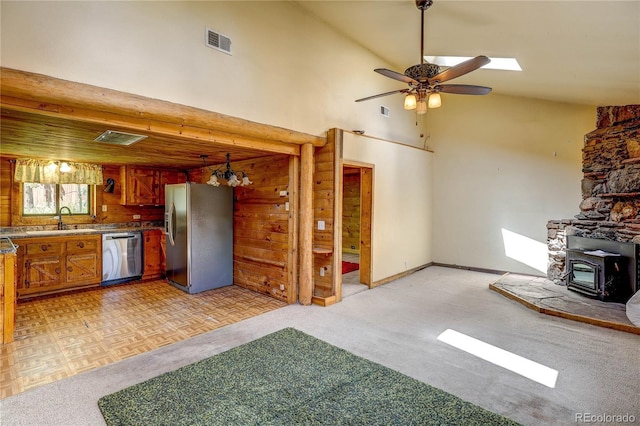 10893 Milliken Ave, Conifer, CO 80433 - kitchen with stainless steel appliances, a wood stove, brown cabinetry, a ceiling fan, and light colored carpet