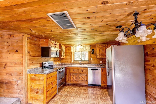 10893 Milliken Ave, Conifer, CO 80433 - kitchen with appliances with stainless steel finishes, wood ceiling, wooden walls, and brown cabinetry