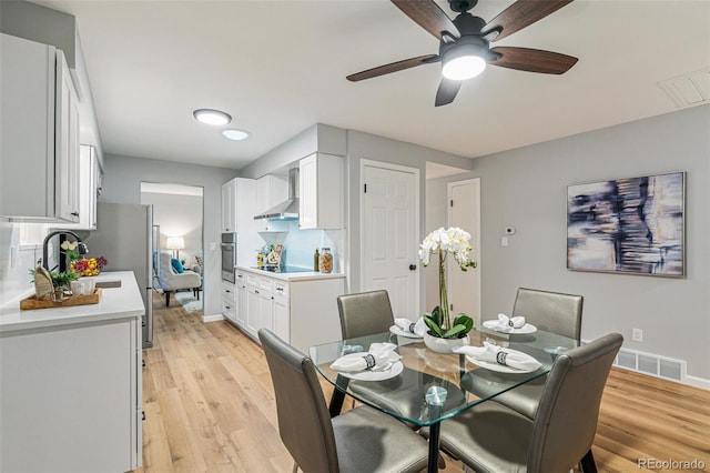 dining area featuring ceiling fan, sink, and light hardwood / wood-style flooring