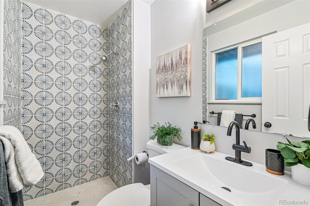 bathroom featuring tiled shower, vanity, and toilet