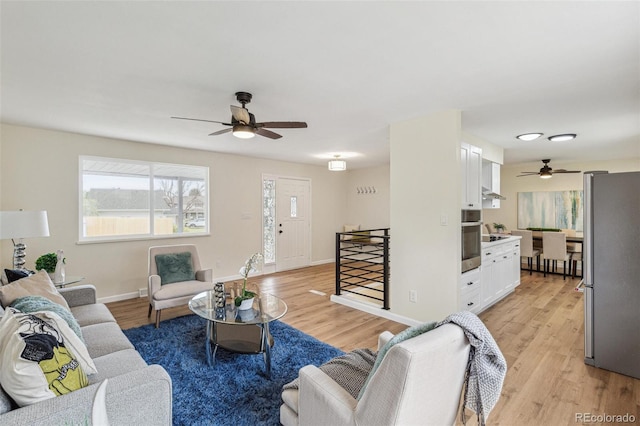 living room with light wood-style floors, baseboards, and ceiling fan