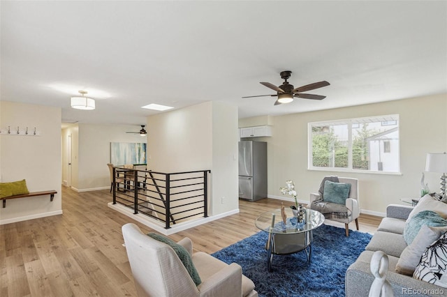 living area with baseboards, ceiling fan, and light wood-type flooring