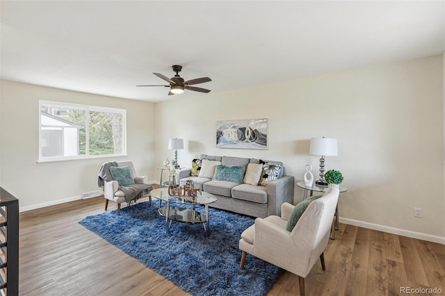 living area with baseboards, ceiling fan, wood finished floors, and visible vents