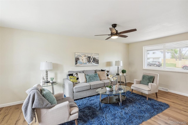 living area featuring baseboards, ceiling fan, wood finished floors, and visible vents