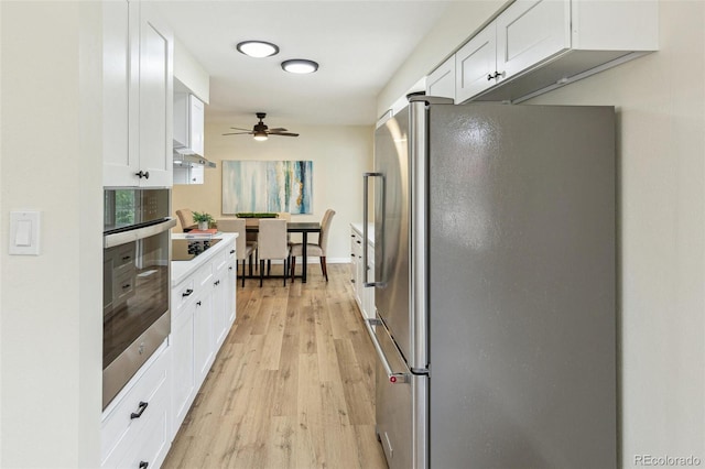 kitchen featuring light wood finished floors, ceiling fan, white cabinets, and stainless steel appliances
