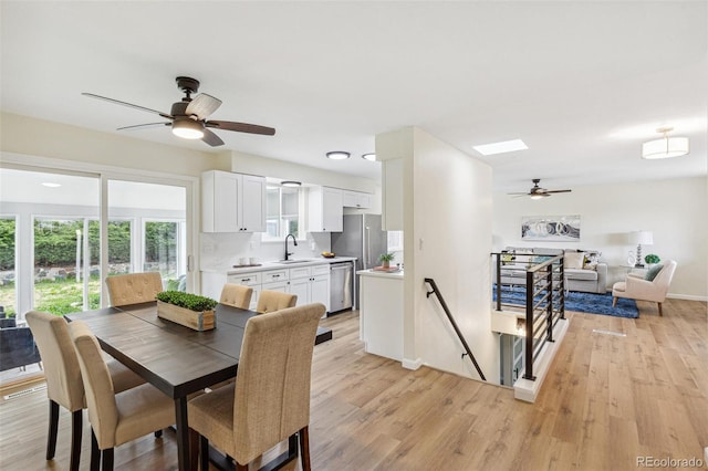 dining space with baseboards, a ceiling fan, and light wood-style flooring