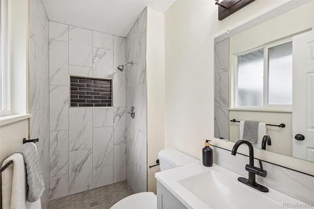 bathroom featuring toilet, a marble finish shower, and vanity