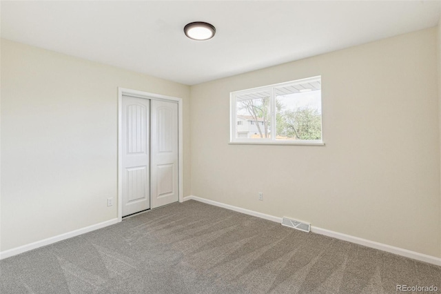 unfurnished bedroom with carpet floors, baseboards, visible vents, and a closet