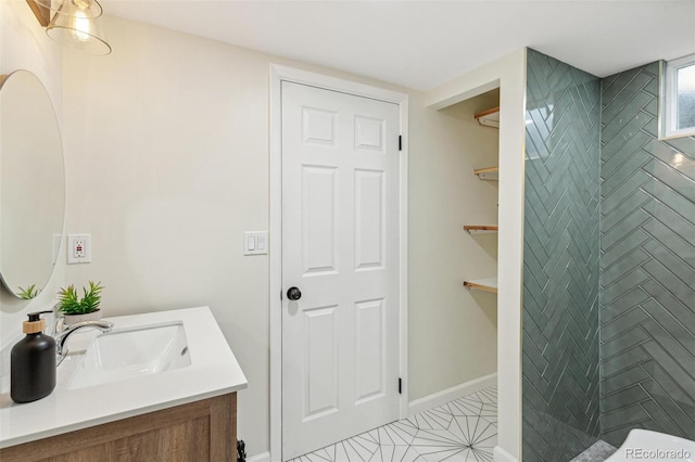 bathroom featuring baseboards, a tile shower, and vanity