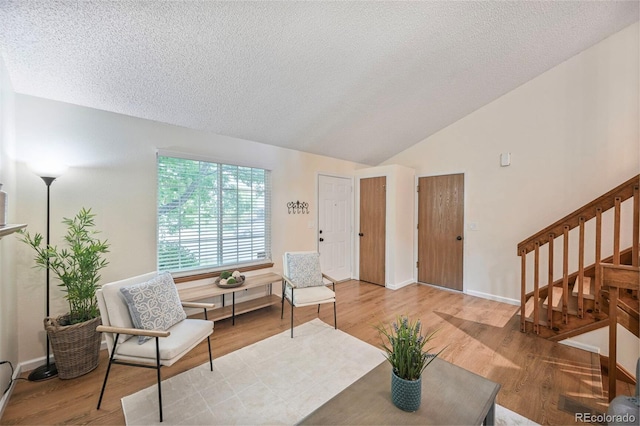 5602 S Yank Ct, Littleton, CO 80127 - living area with lofted ceiling, stairs, wood finished floors, and a textured ceiling