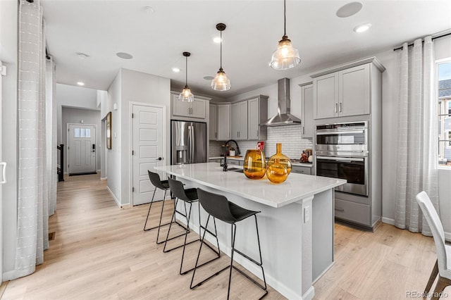 2110 Wagon Wheel Aly, Brighton, CO 80601 - kitchen featuring wall chimney range hood, gray cabinetry, appliances with stainless steel finishes, tasteful backsplash, and recessed lighting
