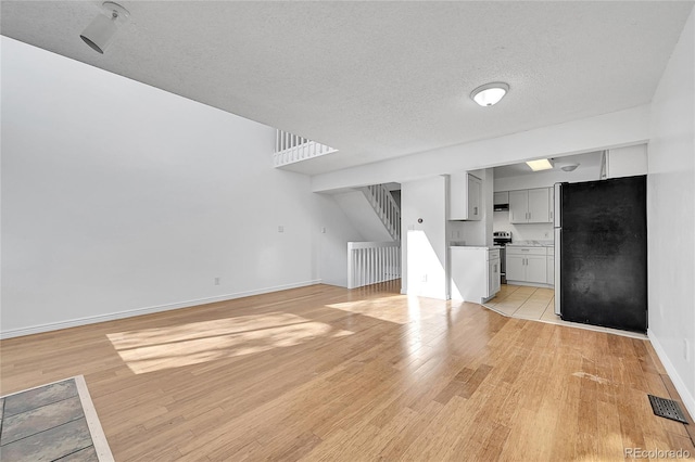 unfurnished living room featuring light hardwood / wood-style floors and a textured ceiling