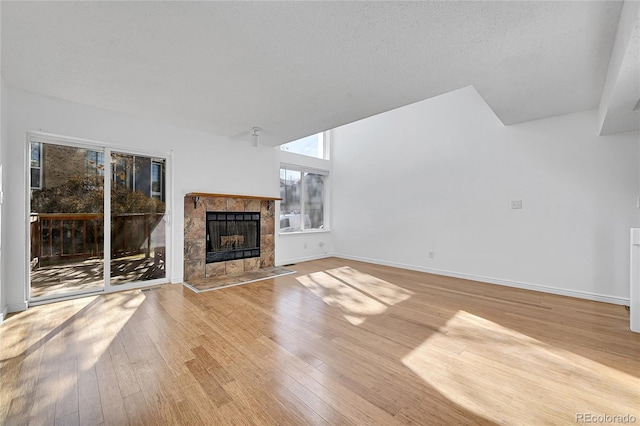 unfurnished living room with a tile fireplace, a textured ceiling, and light hardwood / wood-style floors