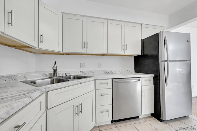 kitchen featuring appliances with stainless steel finishes, white cabinetry, sink, light tile patterned floors, and light stone countertops