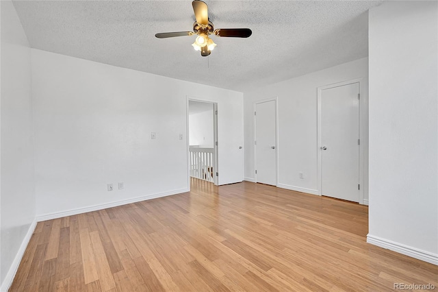 empty room with ceiling fan, a textured ceiling, and light wood-type flooring