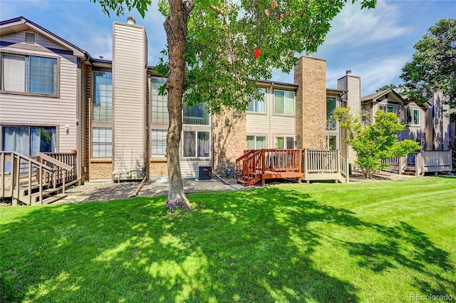 rear view of property with a wooden deck, a yard, and central AC