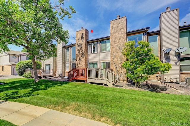 rear view of property featuring a wooden deck and a yard