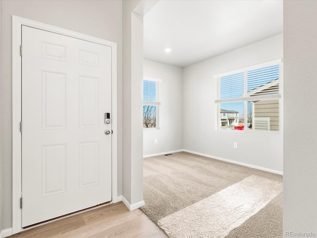 carpeted foyer entrance featuring wood finished floors and baseboards