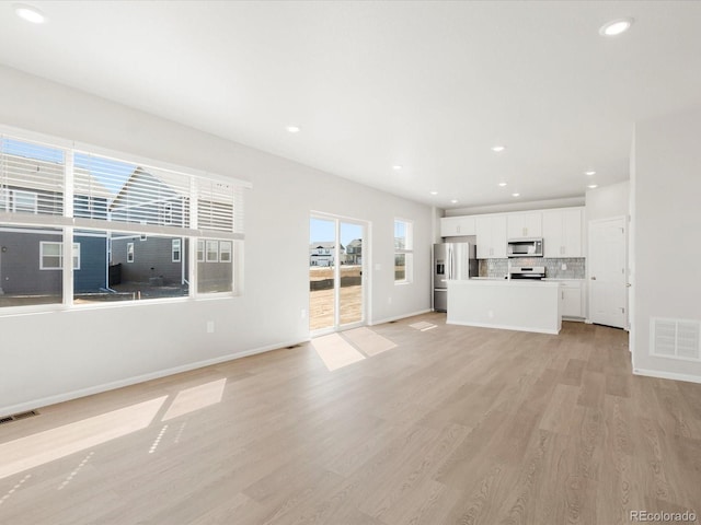 unfurnished living room featuring baseboards, recessed lighting, visible vents, and light wood-type flooring