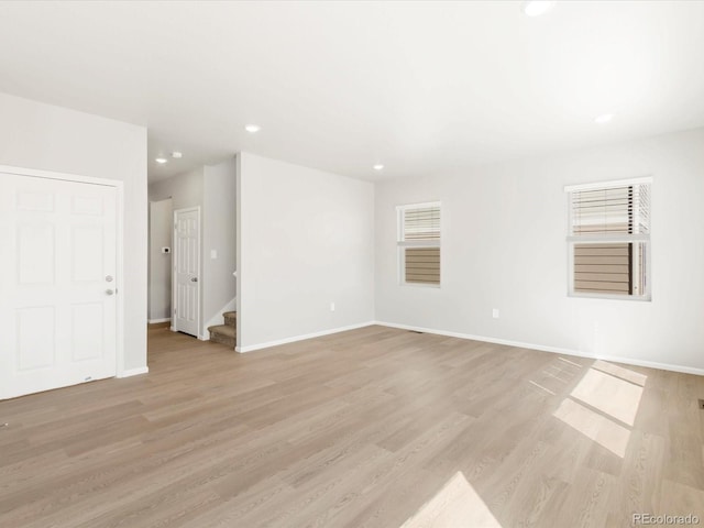 unfurnished room with recessed lighting, baseboards, light wood-style flooring, and stairs