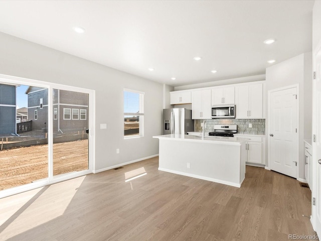 kitchen with white cabinetry, tasteful backsplash, appliances with stainless steel finishes, and light wood finished floors