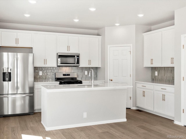 kitchen featuring tasteful backsplash, stainless steel appliances, light wood-style floors, and a sink