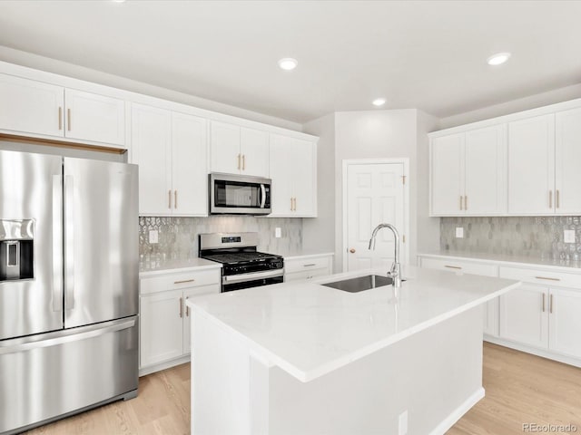 kitchen with a sink, stainless steel appliances, light wood-type flooring, and a center island with sink