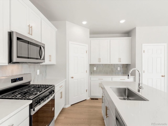 kitchen featuring a sink, appliances with stainless steel finishes, light countertops, and white cabinetry