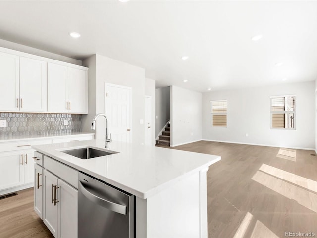 kitchen with visible vents, a sink, stainless steel dishwasher, light wood-style floors, and decorative backsplash