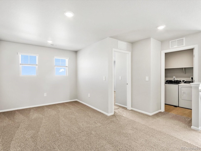 empty room with visible vents, light colored carpet, baseboards, and separate washer and dryer