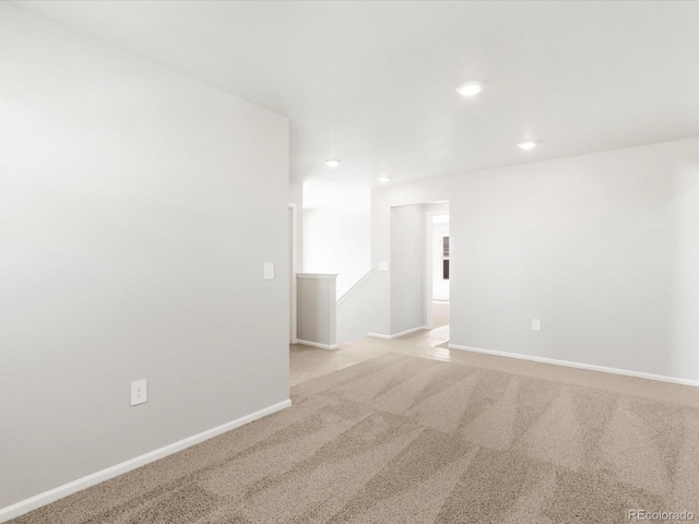 spare room featuring recessed lighting, baseboards, and light colored carpet