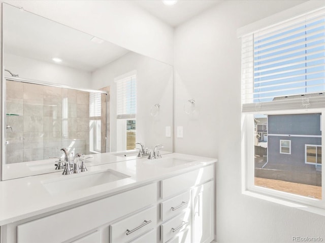 full bathroom featuring double vanity, tiled shower, and a sink