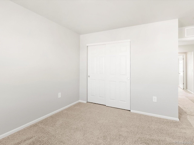 unfurnished bedroom featuring visible vents, carpet, baseboards, and a closet