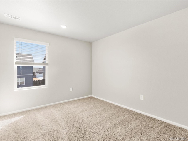 carpeted spare room with visible vents and baseboards