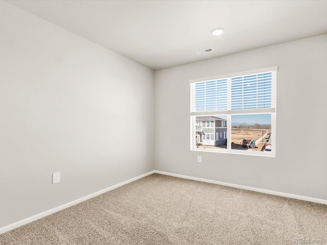 carpeted spare room with visible vents and baseboards