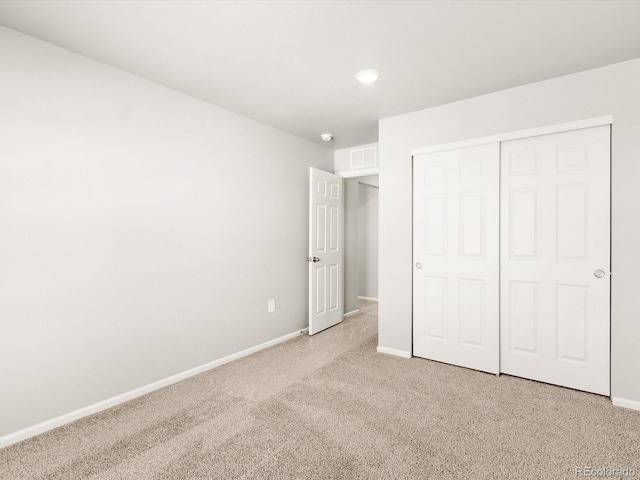 unfurnished bedroom featuring light carpet, visible vents, a closet, and baseboards