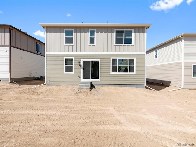 rear view of house with board and batten siding and dirt driveway