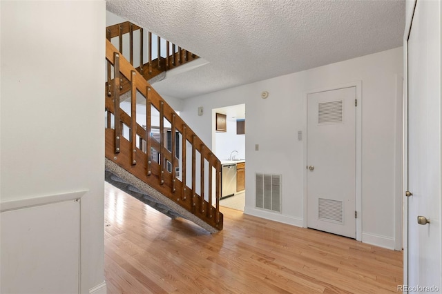 foyer entrance with light hardwood / wood-style flooring and a textured ceiling