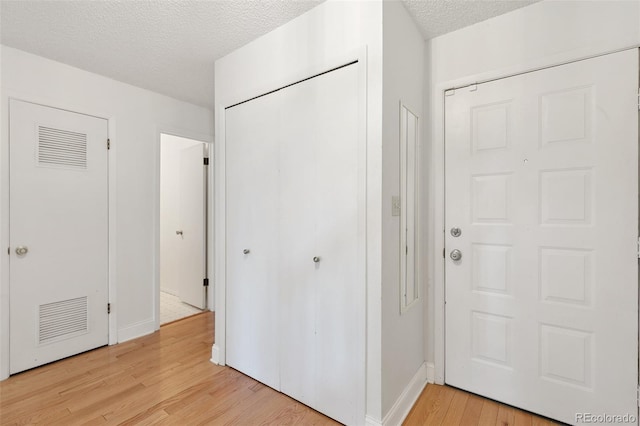 foyer with light wood-type flooring and a textured ceiling