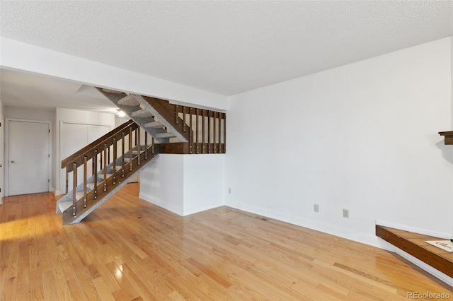 unfurnished living room with light hardwood / wood-style flooring and a textured ceiling