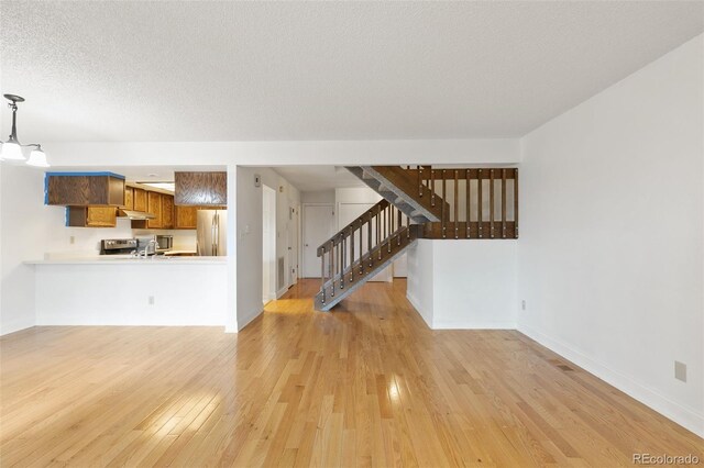 unfurnished living room featuring a textured ceiling and light hardwood / wood-style floors