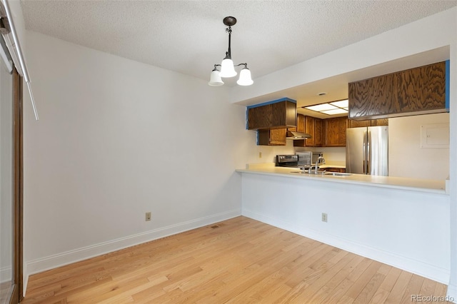 interior space featuring a textured ceiling, stainless steel fridge, an inviting chandelier, light wood-type flooring, and sink