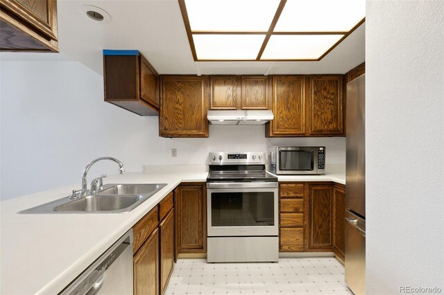 kitchen with appliances with stainless steel finishes, light tile patterned flooring, and sink