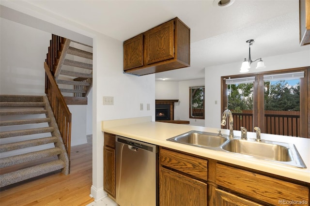 kitchen featuring pendant lighting, dishwasher, light hardwood / wood-style floors, a chandelier, and sink