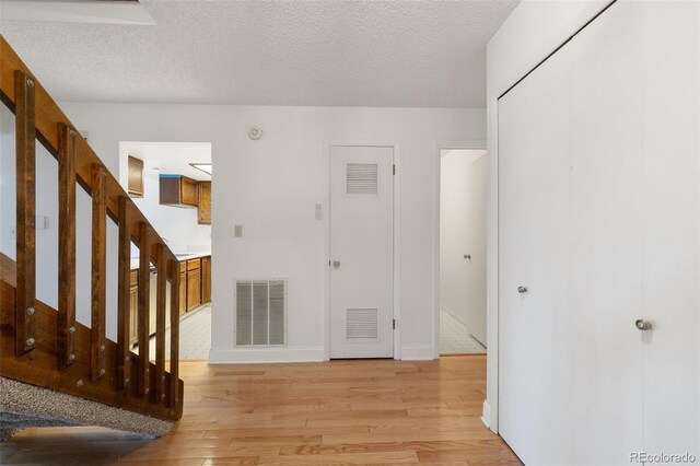 entrance foyer with light wood-type flooring and a textured ceiling