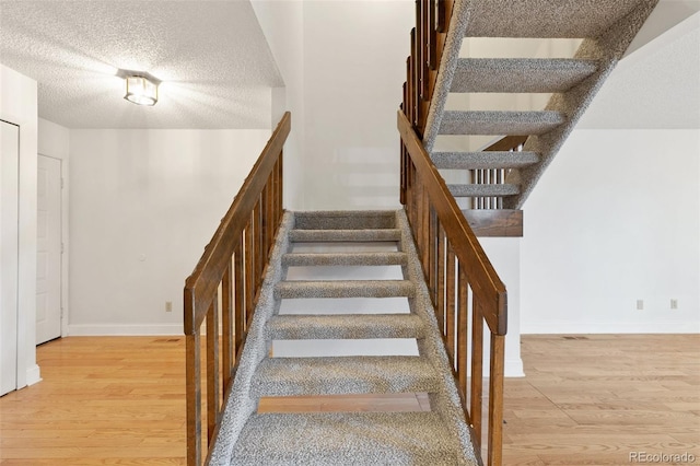 stairs with hardwood / wood-style flooring and a textured ceiling