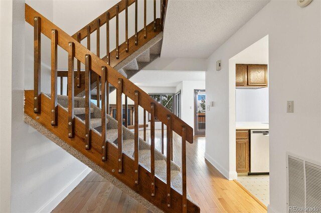 stairway featuring wood-type flooring and a textured ceiling