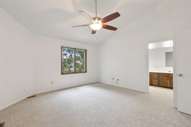 unfurnished bedroom featuring ceiling fan, high vaulted ceiling, ensuite bath, and light carpet