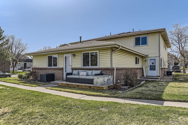 view of front of house with brick siding, a front yard, central AC unit, and an outdoor hangout area